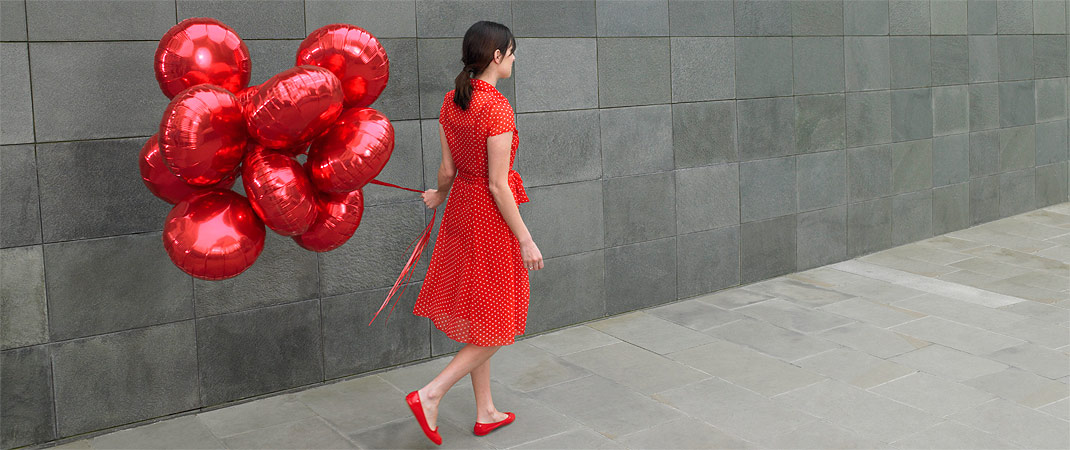Frau mit rotem Kleid, roten Schuhen, roten Luftballons. Beispiel Farbe Rot als Gestaltungsmittel im Corporate Design | Corporate Design . Blufish - Berlin